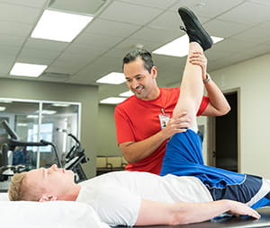 Physical therapist working with person on leg stretches.