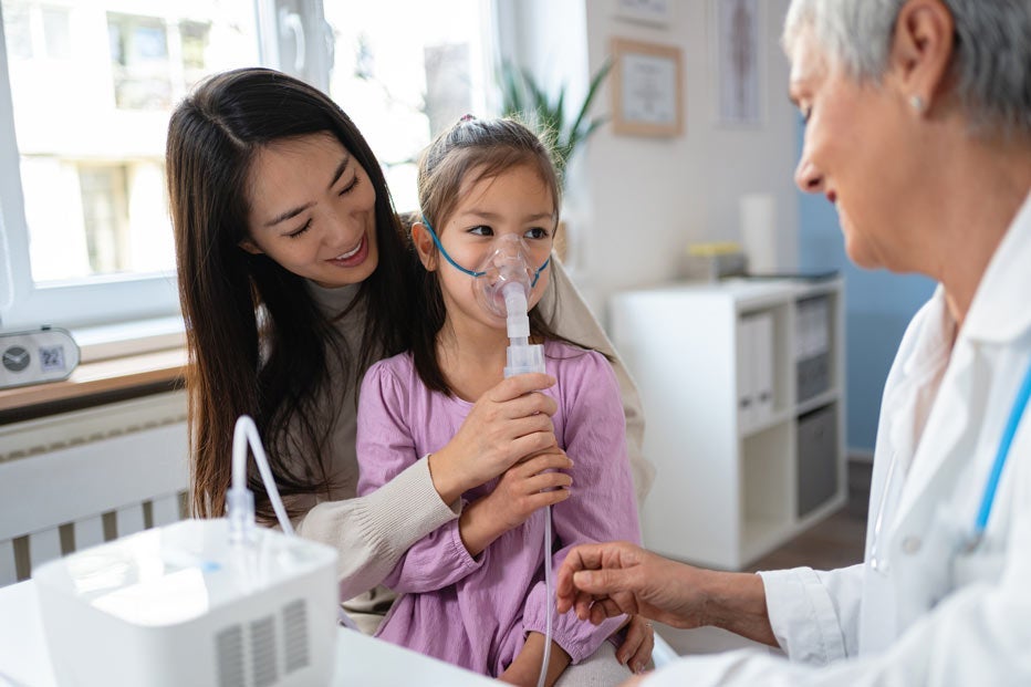 Young girl using nebulizer during medical check-up with pediatrician