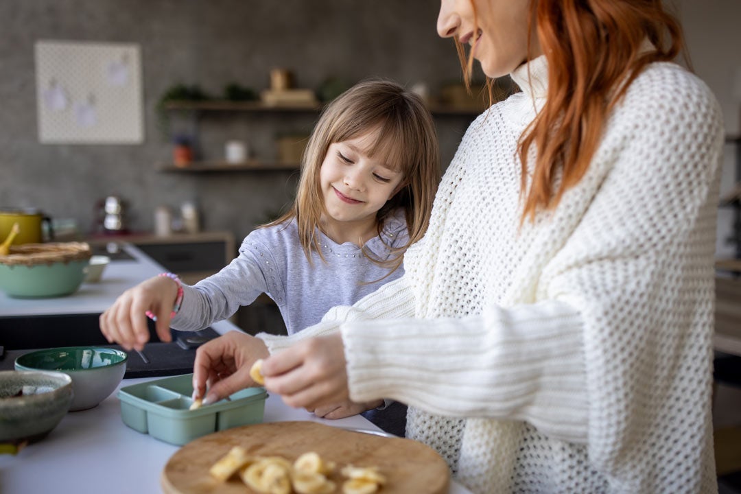 Mother packing lunch with daughter at home
