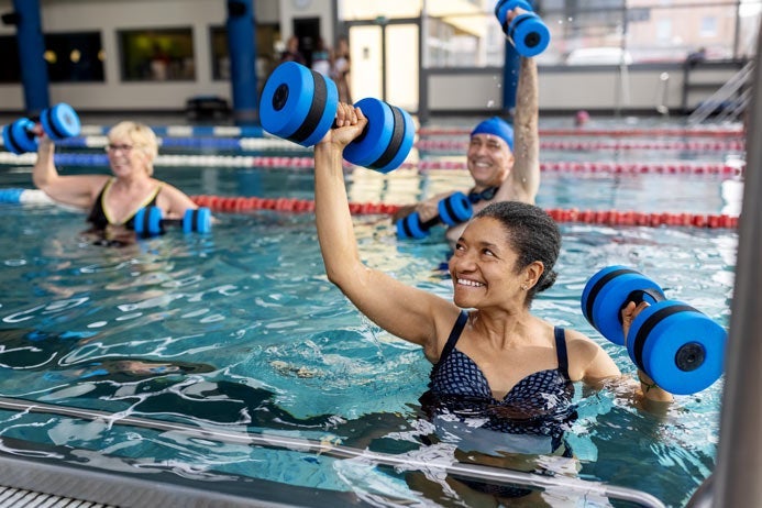 Healthy seniors workout in a swimming pool with aqua dumbbells.