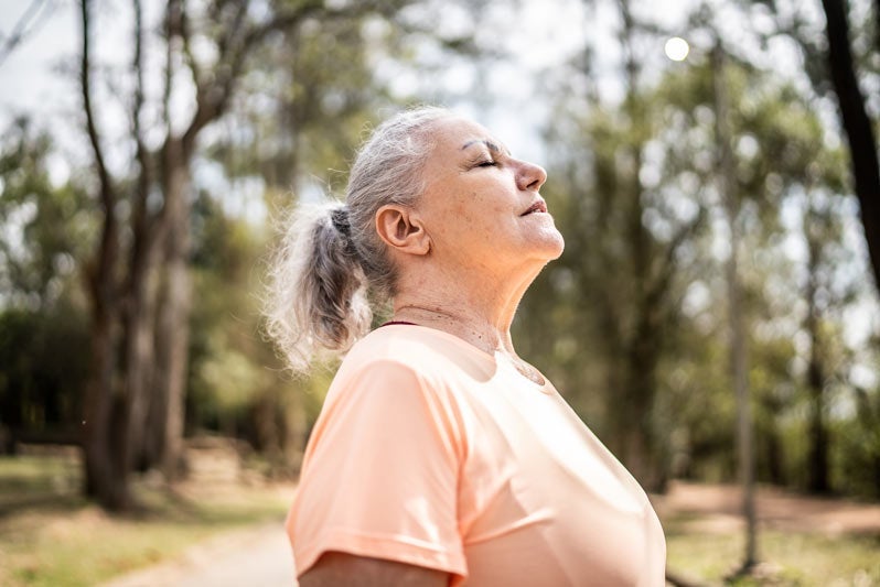 Woman standing outside and staring up at sun with eyes closed