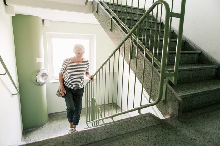 older woman going up the stairs in an apartment building