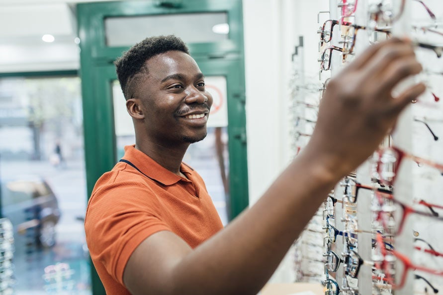 Man in orange shirt looking at eyeglasses