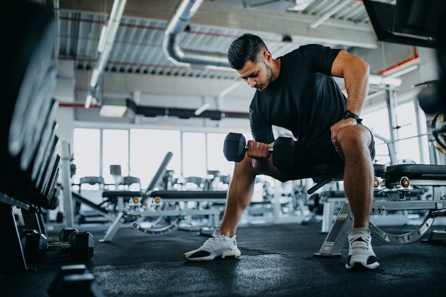 Young man lifting weights in gym